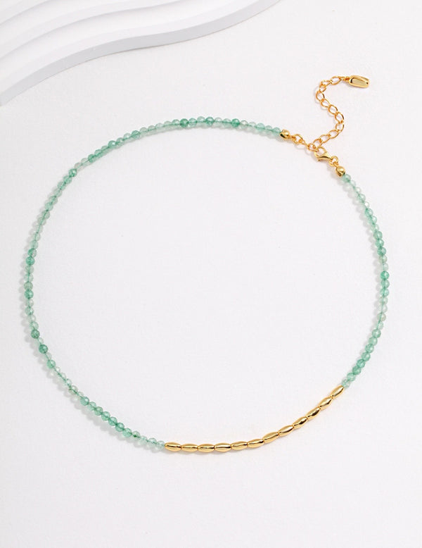 Delicate dual-strand necklace combining translucent green strawberry quartz and a golden chain, finished with an adjustable clasp for a customizable fit.